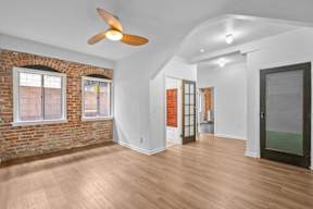 A room with a ceiling fan and wooden floors.
