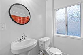 A bathroom with a toilet, sink, and mirror.