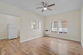 A room with a ceiling fan and a window with blinds.