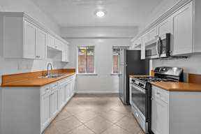 A kitchen with white cabinets and a wooden countertop.