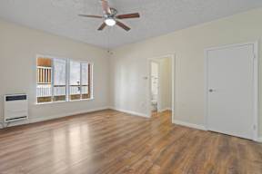 A room with a ceiling fan and wooden flooring.