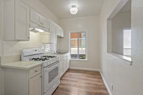 A white kitchen with wood floors and a window.