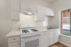 A white kitchen with a stove and cabinets.