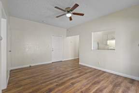 A room with a ceiling fan and wooden floors.
