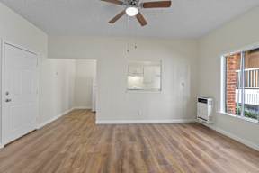 A room with a ceiling fan and wooden floors.