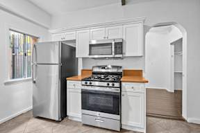 A modern kitchen with a stainless steel refrigerator, microwave, and oven.