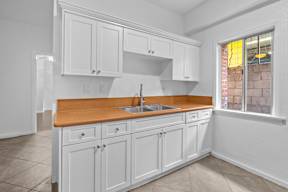 A kitchen with white cabinets and a wooden countertop.