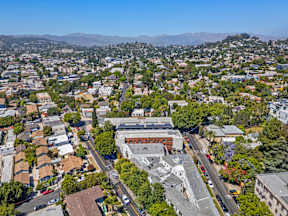 A cityscape with a mix of residential and commercial buildings, surrounded by greenery and mountains in the distance.