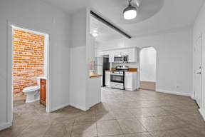 A kitchen with white cabinets and a red brick wall.