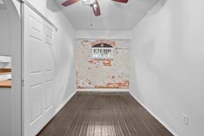 A room with a white wall and a brick wall with a window.