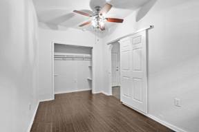 A room with a ceiling fan and wooden flooring.