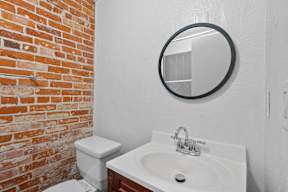 A bathroom with a toilet, sink and mirror.