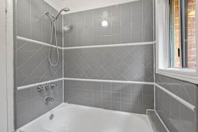 A white bathtub with a shower head and hand held shower.