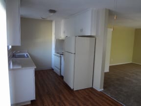 Kitchen with hardwood flooring, white appliances and cabinets at Villa Knolls Apartments in La Mesa, California.