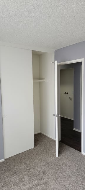 Carpeted bedroom and hallway nook with washer/dryer hookups at Grand Oaks Apartments in Lake Elsinore, California.