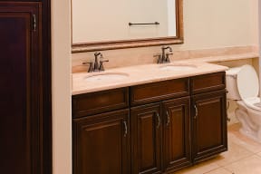 Bathroom with double sinks and dark wood cabinets at Carmel Heights Apartments in San Diego, California.