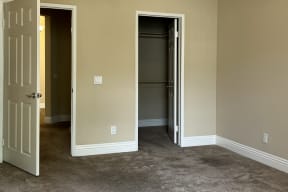 Carpeted bedroom with walk-in closet at Carmel Heights Apartments in San Diego, California.