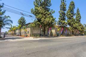 A street view with a building on the right and trees on the left.