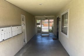 Entrance hallway with mailboxes and security door to front yard at Eucalyptus Apartments in Moreno Valley, California.
