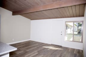 Front room with hardwood floor and exposed wood ceiling at Harbor Villa Apartments in San Diego, California.