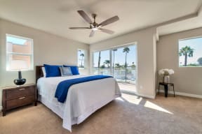 Carpeted bedroom with ceiling fan and sliding glass doors to porch at Villa Grande Apartments in San Diego, California.