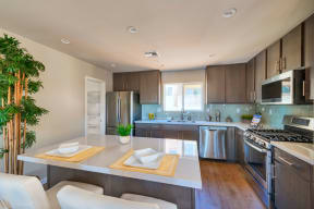 Kitchen with large island and plank style flooring with pantry at Villa Grande Apartments in San Diego, California.