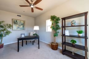 Carpeted bedroom/study with ceiling fan at Villa Grande Apartments in San Diego, California.