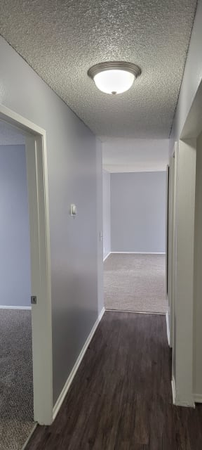 Hallway view of two carpeted bedrooms at Grand Oaks Apartments in Lake Elsinore, California.