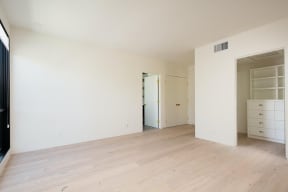 Bedroom with walk-in closet, large windows and wood plank style flooring in apartment at 633 Palms Blvd. in Venice, California.