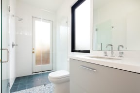 Bathroom with walk-in shower, white tile and modern white fixtures in apartment at 633 Plams Blvd. in Venice, California.