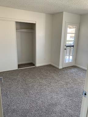 A room with a carpeted floor and a door leading to a balcony.