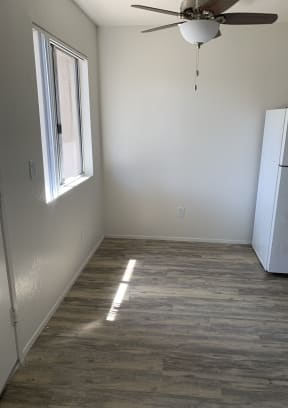 Dining area with plank style flooring, lots of natural light and ceiling fan at Carlsbad Sunset Senior Apartments in Carlsbad, California.