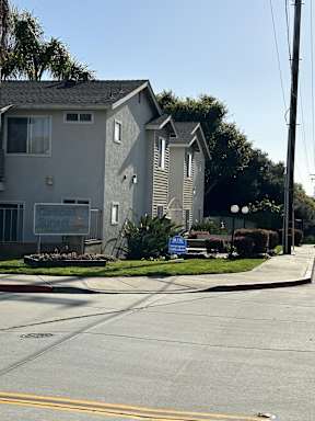A street view of a residential area with a house and a sign that says "Canyon Sunset".