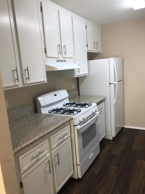 Beautiful white kitchen cabinets, white gas range and refrigerator at Grande Vista Apartments.