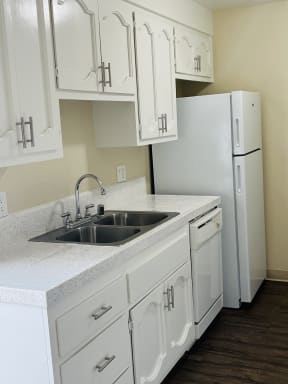Kitchen with white cabinets and appliances at Plaza Verde Apartments in Escondido, California.