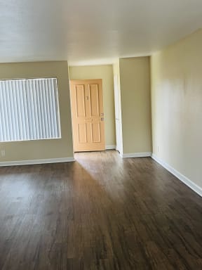 Living room with large window and entry closet with plank style flooring at Plaza Verde Apartments in Escondido, California.