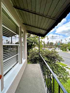 A balcony with a metal railing and a view of the street below.