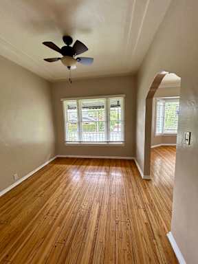A room with a ceiling fan and wooden flooring.