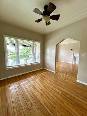 A room with a ceiling fan and wooden flooring.