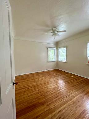 A room with a ceiling fan and wooden flooring.