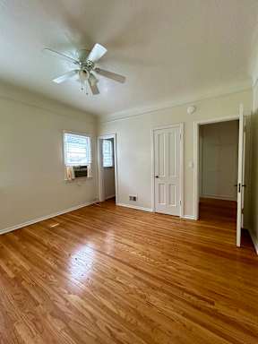 A room with a ceiling fan and wooden flooring.