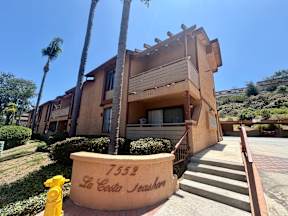 A yellow fire hydrant is in front of a house with the number 7552 and the name La Costa Neighborhood written on it.