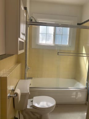 Bathroom with a toilet and a bathtub with vintage yellow tile at 900 Taylor Street Apartments.
