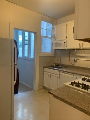 White kitchen cabinets and white appliances and laundry room with stacked washer and dryer at 900 Taylor Street Apartments in San Francisco.