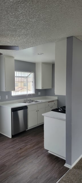 Kitchen and dining area with hardwood style flooring at Grand Oaks Apartments in Lake Elsinore, California.