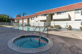 A small pool with a ladder in front of apartment buildings.