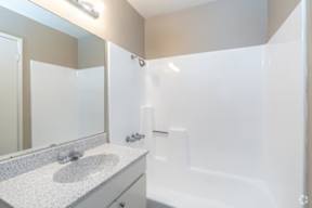 A white bathroom with a sink, mirror, and bathtub.
