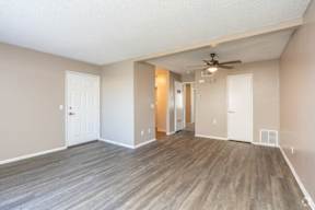 A room with a ceiling fan and wooden flooring.