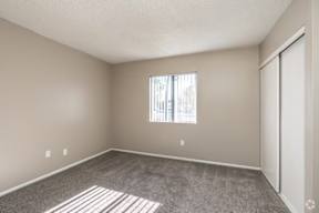 A room with a window and a carpeted floor.