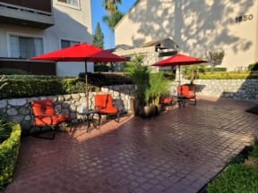 Serene sitting area with brick patio and lush gardens at Northwood Apartments in Upland, California.